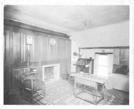 SA0520 - Shows a room interior with a bed, small fireplace, desk, corner chair, and table., Winterthur Shaker Photograph and Post Card Collection 1851 to 1921c